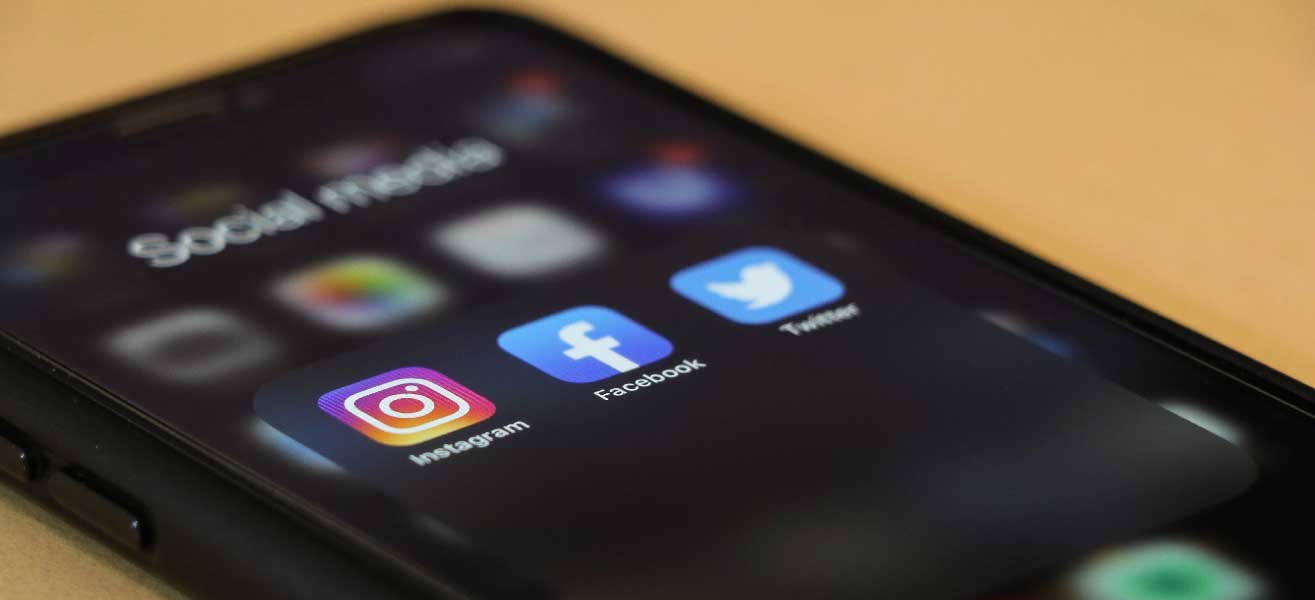 Photo représentant, sur un écran de smartphone, les icônes de réseaux sociaux, pour illustrer le fait que l'utilisation de ces derniers augmente la visibilité d'une marque.