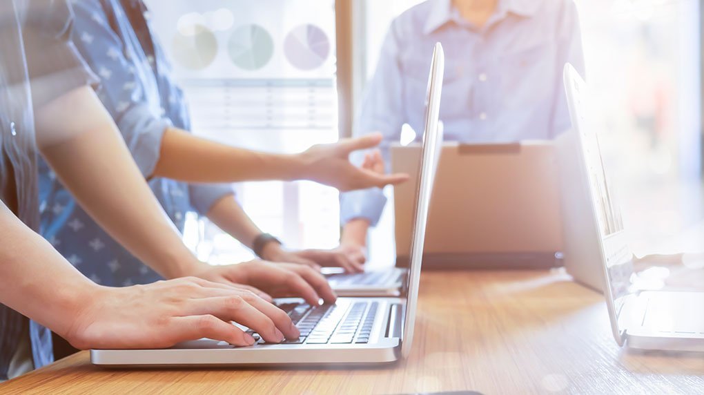 photo représentant des personnes consultant leur ordinateur portable, et illustrant une réunion de travail dédiée au site web d'une entreprise